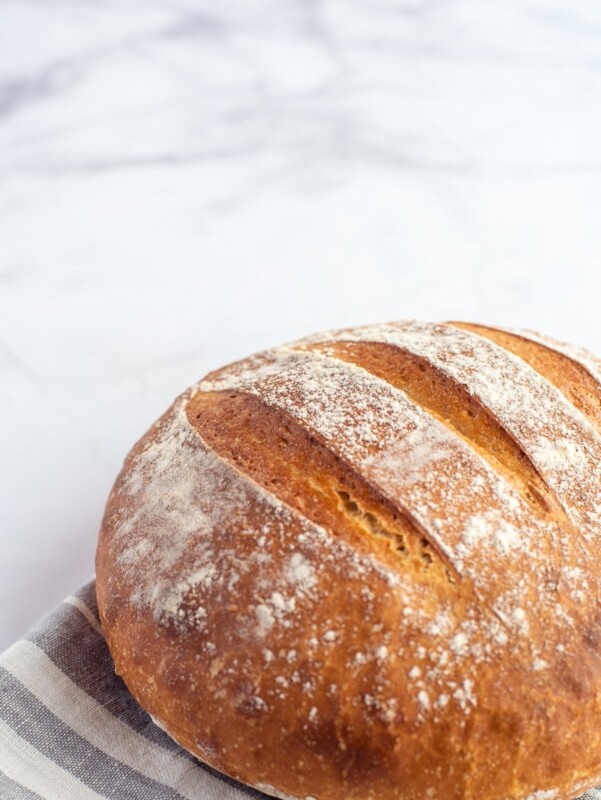 Homemade whole-wheat yoghurt bread with a golden crust, lightly dusted with flour and scored across the top.
