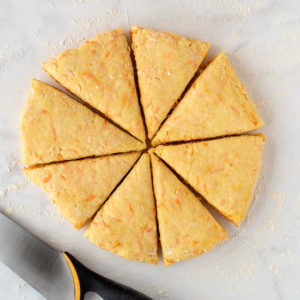 Round tahini and carrot scone dough cut into eight triangular wedges.