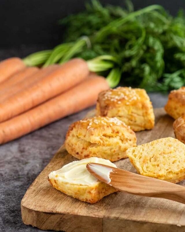 Savoury tahini and carrot scones with fresh carrots and a warm scone spread with butter.