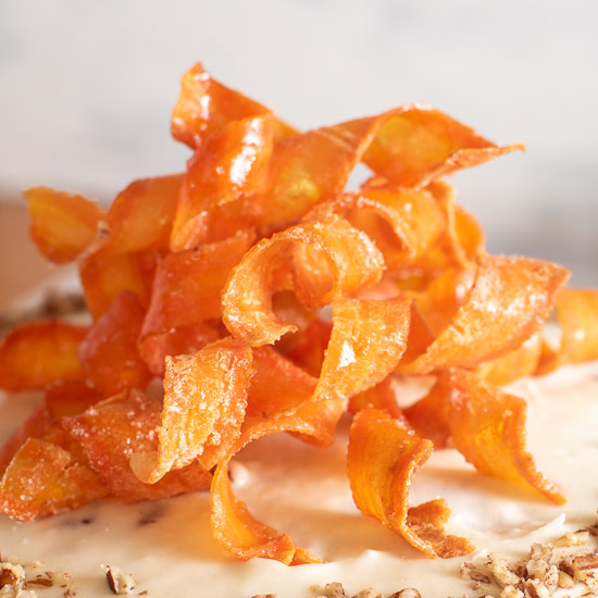 Glossy orange candied carrot curls prepared for decorating carrot cake.